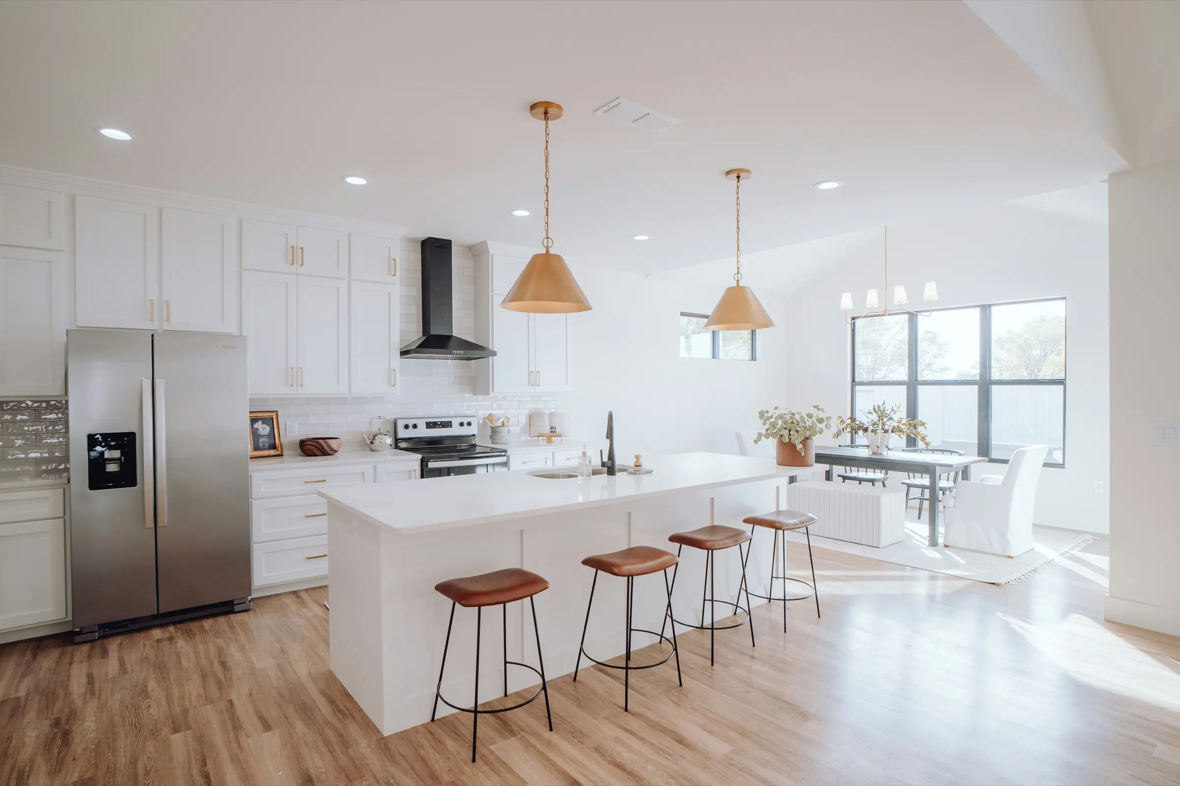Une cuisine ouverte et lumineuse, plan de travail net et tabourets en bois